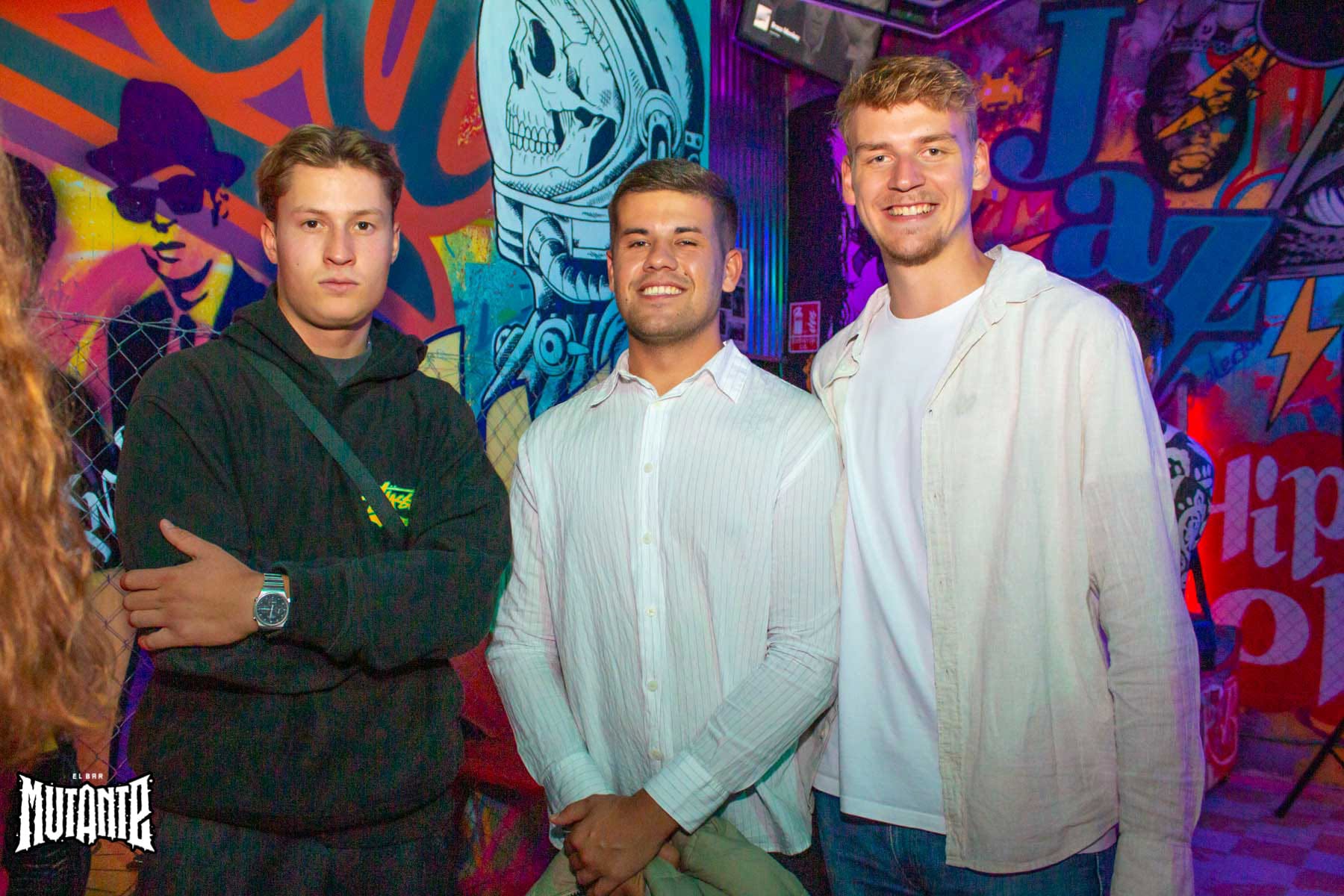 Three friends standing together at an evening gathering